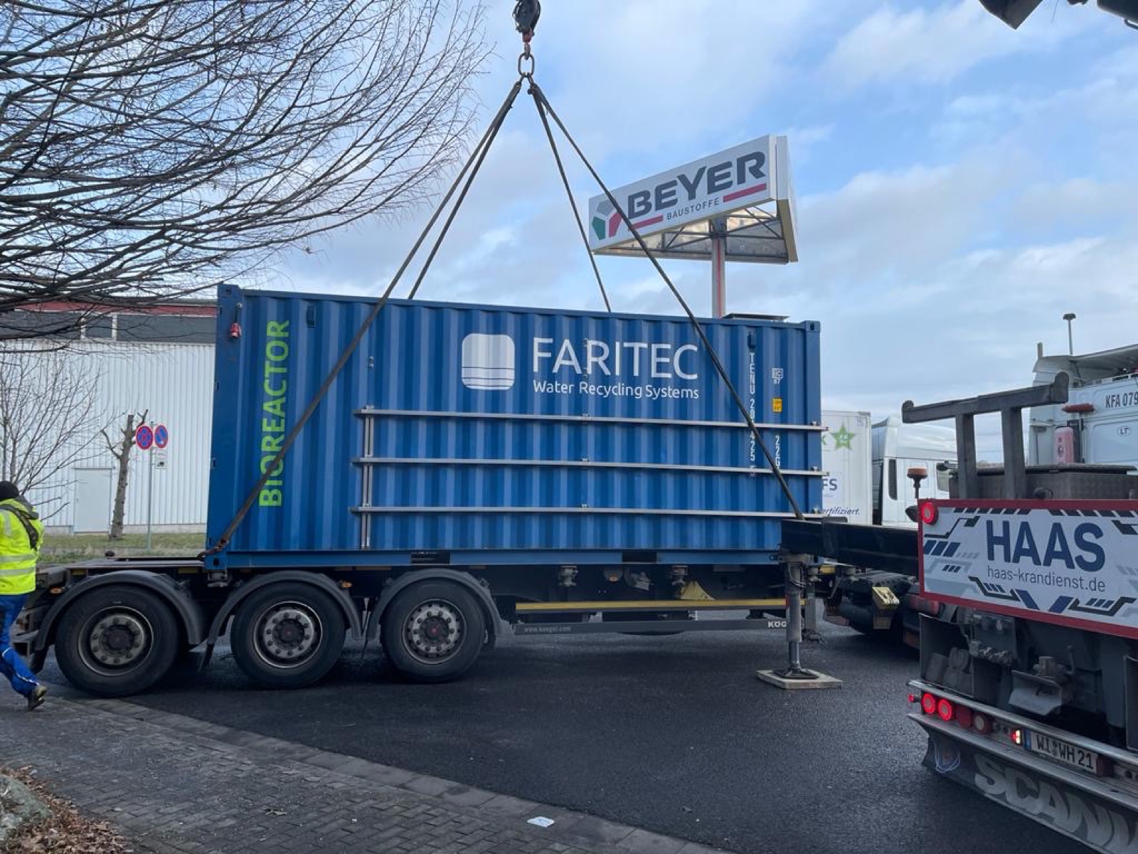 Blauwe FARITEC-bioreactorcontainer op een vrachtwagen tijdens het laden met een kraan
