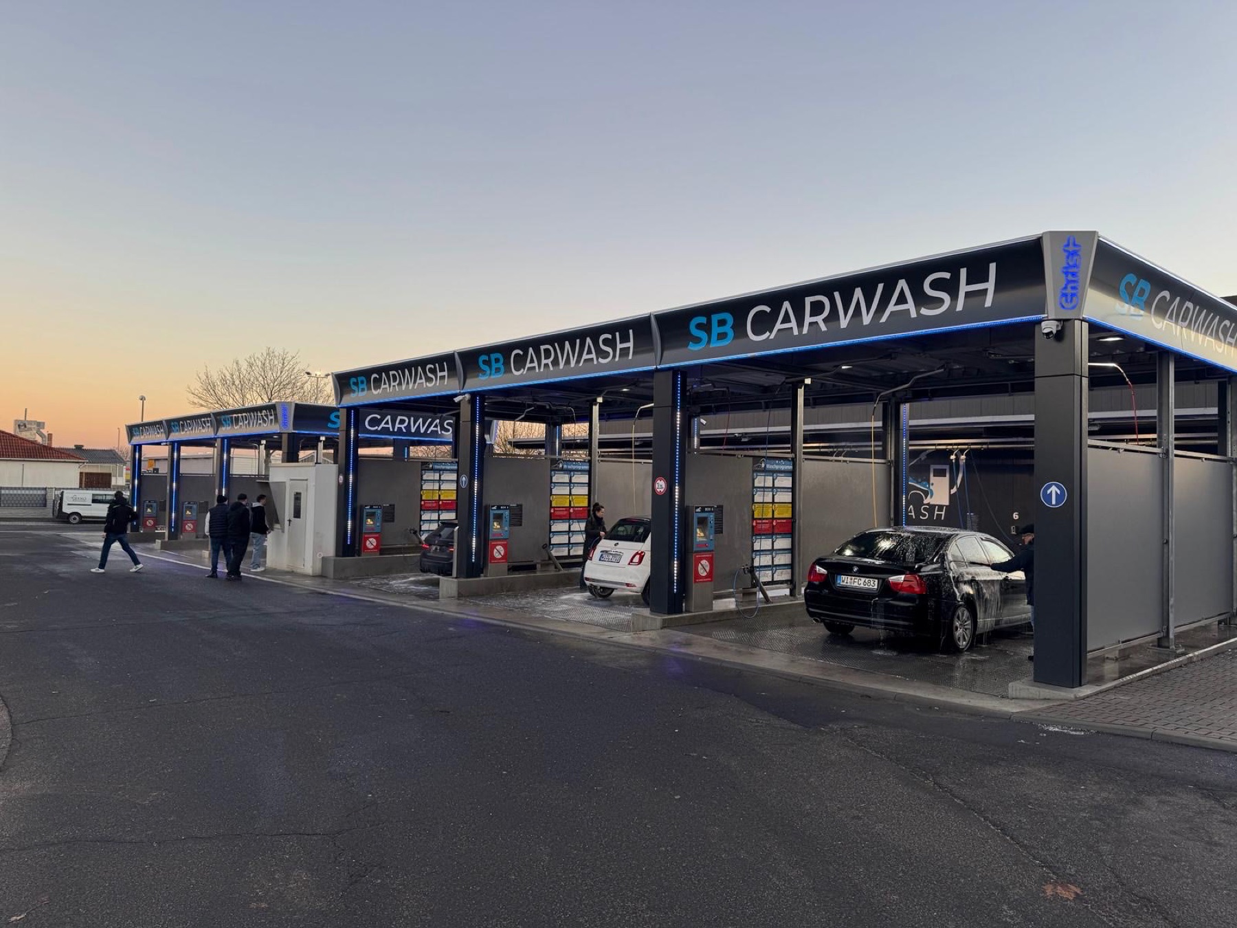 Centro de lavado de autoservicio con varias pistas y paneles de control iluminados